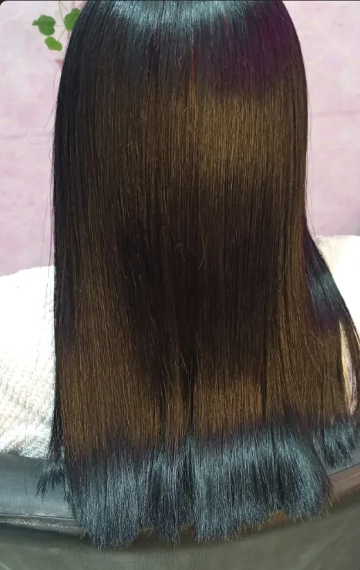 Cabelo escuro alinhado e brilhoso após uso de produto Hadar